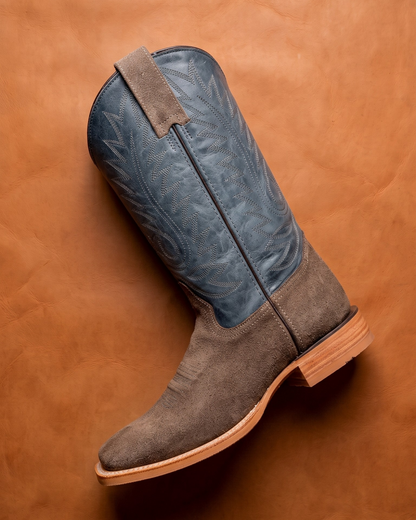 Gray and blue cowboy boot on a brown leather background