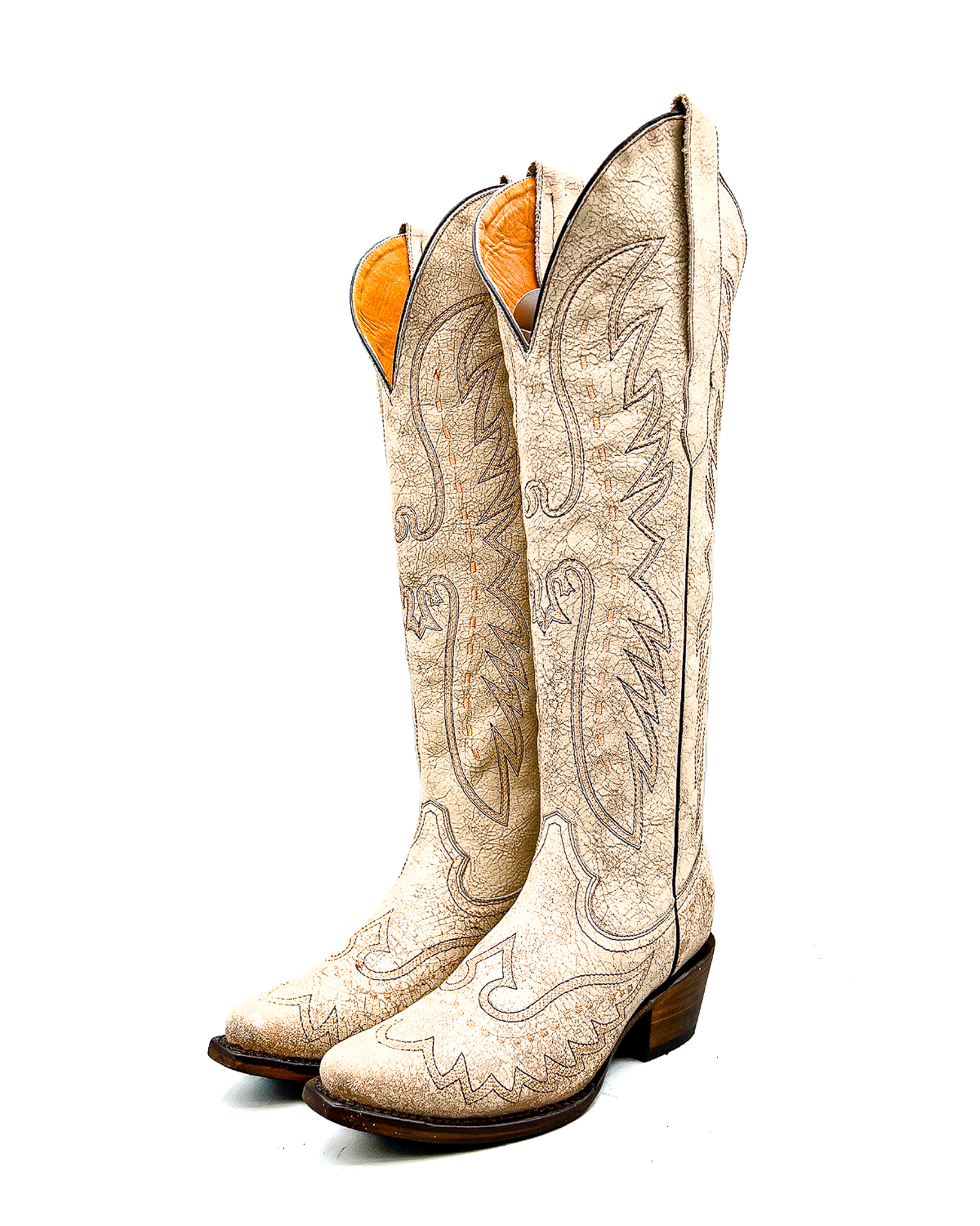 Pair of white tall cowboy knee high boots with intricate designs on a white background