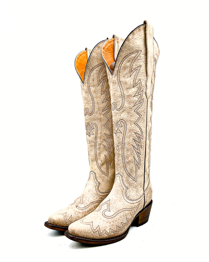 Pair of white tall cowboy knee high boots with intricate designs on a white background